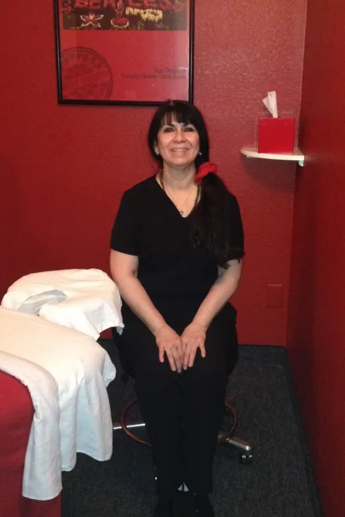 A woman seated in a chair, with a vibrant red wall as the backdrop.